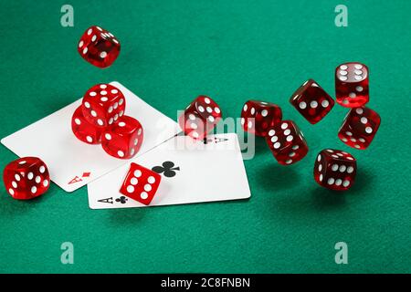 rolling red dice over green felt and two aces Stock Photo