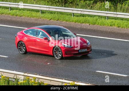 2019 red Tesla Model 3 Performance AWD Vehicular traffic moving vehicles, cars driving vehicle on UK roads, motors, motoring on the M6 motorway highway network. Stock Photo