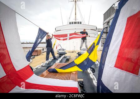 Tony Smith (left) and Rab McAulay, from the maintenance team, raise the dress flags on The Royal Yacht Britannia to mark the Edinburgh visitor attraction reopening to members of the public on Monday 27 July. Stock Photo