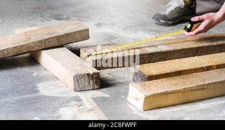 Woman in a home workshop measuring tape measure wooden board before sawing. Stock Photo