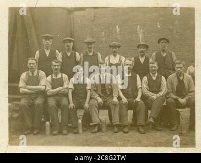 Early 1900's postcard of working class men outside in yard wearing flat caps, with flasks, circa 1907, U.K.