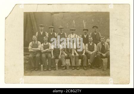 Early 1900's postcard of working class men outside in yard wearing flat caps, with flasks, circa 1907, U.K. Stock Photo