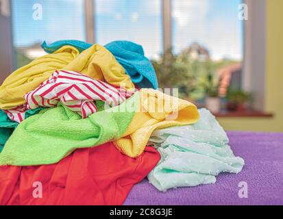 Stack of laundry for ironing on an ironing board. Stock Photo