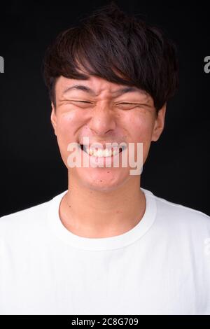 Young handsome Asian man against black background Stock Photo