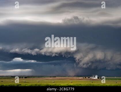 Wall clouds spin below a tornado super-cell hovering and kicking up ...