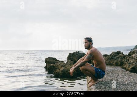 Man sitting on edge of sea Stock Photo