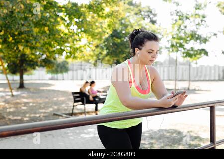 Woman using cellphone in park, friends taking break in background Stock Photo