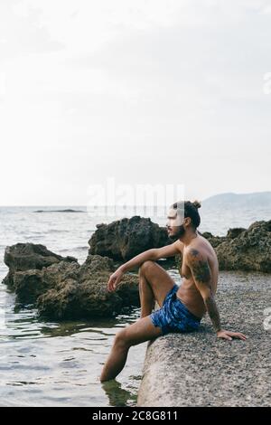 Man sitting on edge of sea Stock Photo