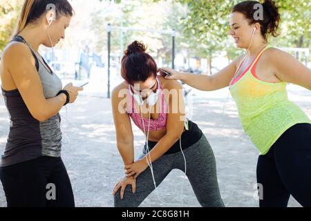 Friends exercising and using cellphone in park Stock Photo