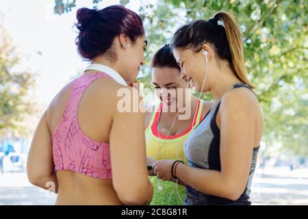 Friends exercising and using cellphone in park Stock Photo