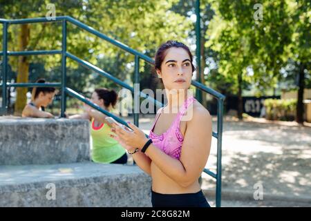 Woman using cellphone in park, friends taking break in background Stock Photo