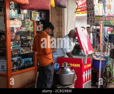 Trichy, Tamil Nadu, India - February 2020: An elderly Indian man selling ice cream to a customer on the roadside outside a shop in Tiruchirappalli. Stock Photo