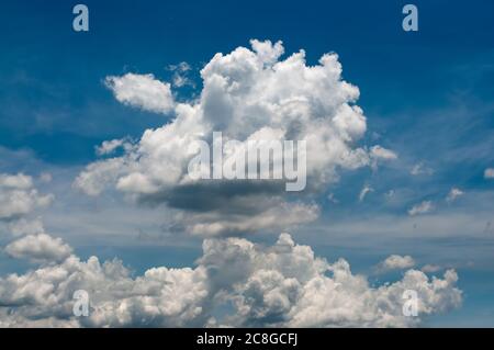 White puffy clouds on a vivid blue sky in sunny day. Stock Photo