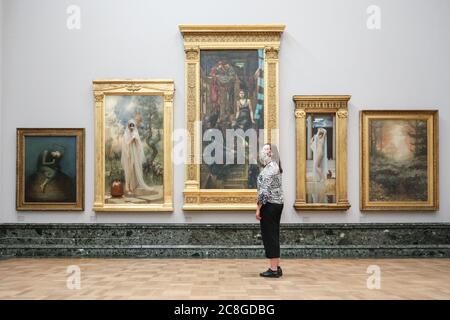 London, UK. 24th July, 2020. An assistant looks at various works in the Pre-Raphaelite collection. Tate Britain, along with other Tate Galleries in the country will re-open to visitors from Monday, 27th July with social distancing measures in place. Credit: Imageplotter/Alamy Live News Stock Photo