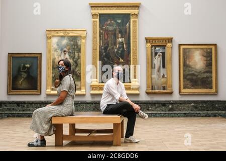 London, UK. 24th July, 2020. Two assistants sit in the Pre-Raphaelite room. Tate Britain, along with other Tate Galleries in the country will re-open to visitors Monday, 27th July with social distancing measures in place. Credit: Imageplotter/Alamy Live News Stock Photo