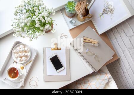 Flat lay, top view office table desk. Workspace with blank clip board, office supplies, pencil, telephone and cup of tea on white background. Stock Photo