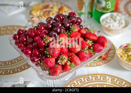 Fresh summer fruits: cherries, organic strawberries crystal bowl . Strawberries and cherries in a crystal bowl. Stock Photo