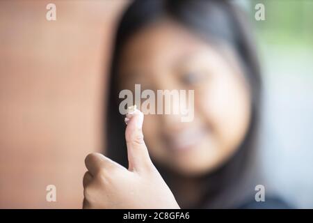 One small frog perched on the girl's finger. The concept of animal love and animal conservation Stock Photo