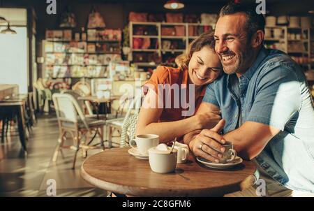 Couple spending quality time together in a coffee shop. Man and woman sitting at cafe table and smiling. Stock Photo