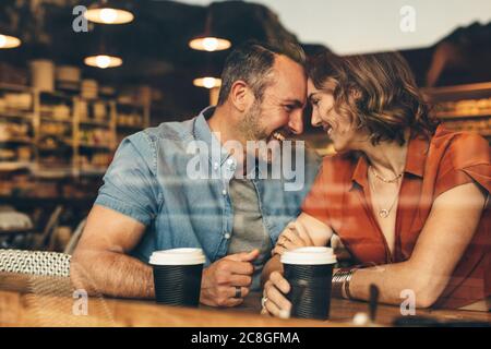 Loving couple on a  date at coffee shop. Couple sitting at cafe touching foreheads and smiling. Stock Photo