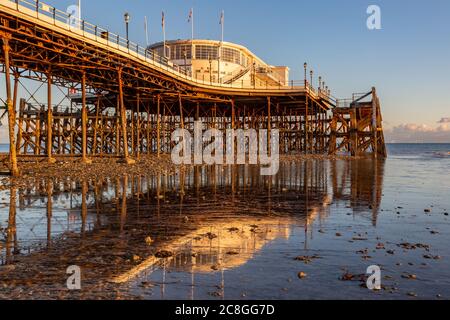 Worthing, Sussex UK-September 24th 2018 Worthing Pier at low tide with evening light, and its reflection in the shallow water Stock Photo