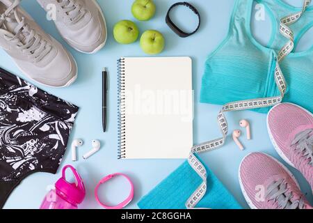 Gym wear and accessories for women with blank notebook for exercise plan on blue background Stock Photo