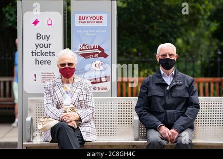 Edinburgh, Scotland, UK. 24 July, 2020. Senior couple sitting at tram stop social distancing themselves and wearing facemasks.  Iain Masterton/Alamy Live News