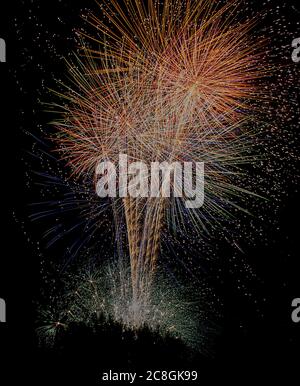 Several colorful fireworks exploding in the dark sky in the middle of the night. The explosions light the sky creating colorful figures, objects and d Stock Photo
