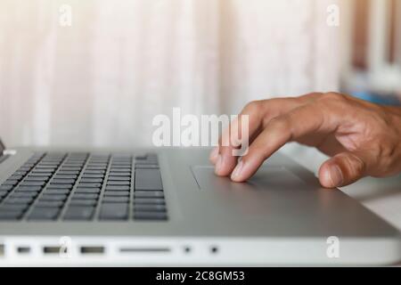 Close up Man hands use touch pad on laptop working at home. Hands touch touch pad use internet for cloud data social network media searching. Work fro Stock Photo