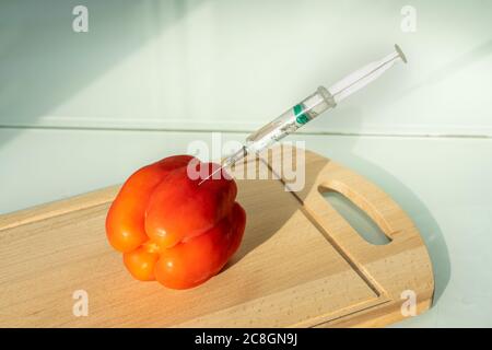 bell pepper and syringe on wooden board. GMOs Stock Photo