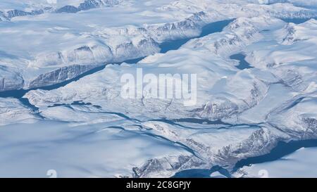 Aerial view of the glaciers, rivers and icebergs on the south coast of Greenland from the window of an airplane from UK to San Francisco Stock Photo