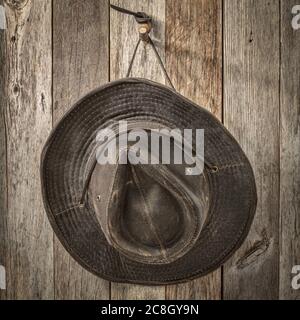 weathered outback oilskin hat hanging on rustic barn wall, monochromatic image in square format Stock Photo