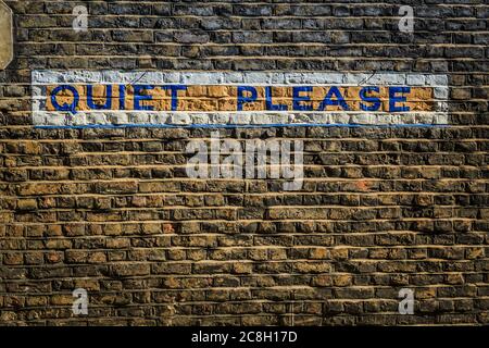 Grungy brick wall with the words "Quiet Please" painted/written in block letters on a city wall.  Taken in London. Stock Photo