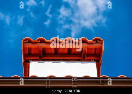 Brown tile roof under blue sky. The photo is divided on two part. One part is a roof made of clay tiles and the other is a blue sky. Brown surface of Stock Photo