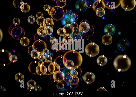 Many rainbow soap water bubbles on isolated dark black background Stock Photo