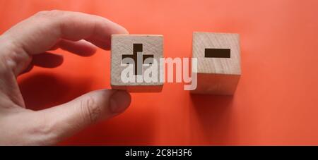 Wooden block in hand on red with plus and minus signs. Decision making concept Stock Photo
