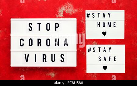 STOP CORONA VIRUS, STAY HOME and STAY SAFE written in light box on bright red background. Healthcare and medical concept. Top view. Quarantine concept Stock Photo