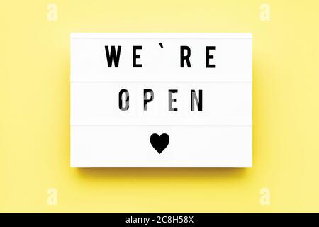 WE'RE OPEN written in light box on yellow background. End of quarantine concept. Copy space, top view Stock Photo