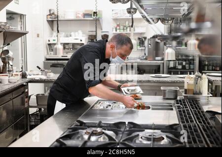 Chef in uniform cooking in a commercial kitchen. Male cook wearing apron standing by kitchen counter preparing food. High quality photo