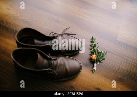 A budier with a rose for the groom, against the background of brown linoleum and men's shoes. Stock Photo