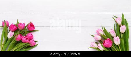 Two bouquets of pink tulips on white wooden background. Mothers day, Valentines Day, Birthday celebration concept. Copy space for text, top view. Bann Stock Photo