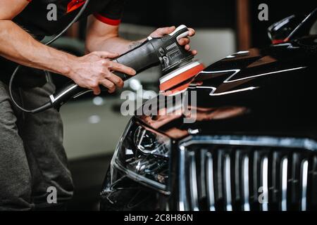 Professional detailing a car in car studio, hands with orbital polisher, scratching remover, vehicle care concept Stock Photo