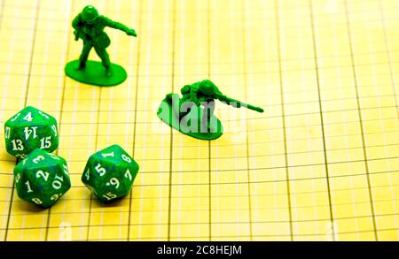 Role-playing field with pentagonal-shaped green dice and miniatures on top of the board Stock Photo