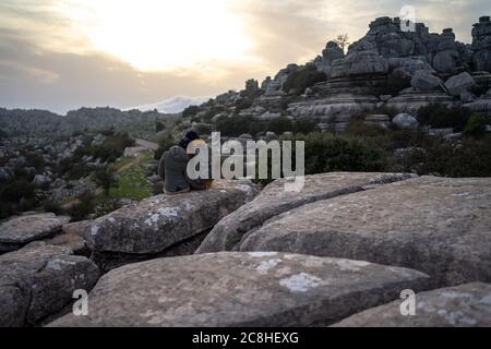 Rear view of couple sitting on rock during sunset Stock Photo