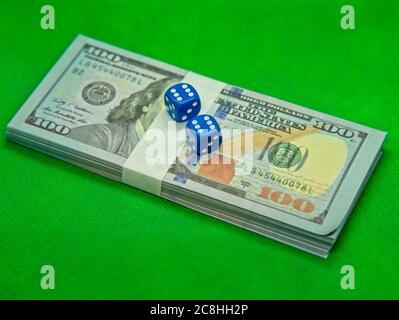 Two dices on top of hundred dollar bills with a green background Stock Photo