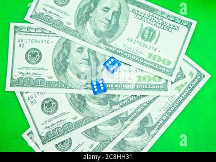 Two dices on top of hundred dollar bills with a green background Stock Photo