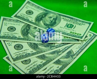 Two dices on top of hundred dollar bills with a green background Stock Photo