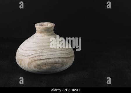 Empty wooden vase on a dark texture table on a black background with space for text. Home interior. Stylish designer vase in light brown in the home c Stock Photo