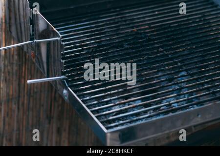 Part of dirty Barbecue Grill Grate after cooking. Empty grill grate. Side view of a barbecue grill grate with lava stones beneath it, lit by sunlight. Stock Photo