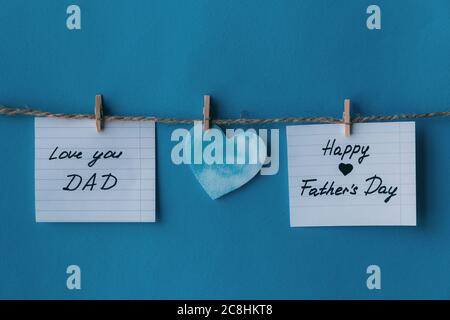 Two white notebook in line paper greeting card with black handwritten lettering happy fathers day and I love you dad hanging on brown rope with clothe Stock Photo